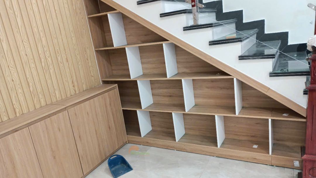 Thi công tủ cầu thang số MDF tông màu sồi kết hợp trắng. Thiết kế kệ trang trí với nhiều khoang trống decor
