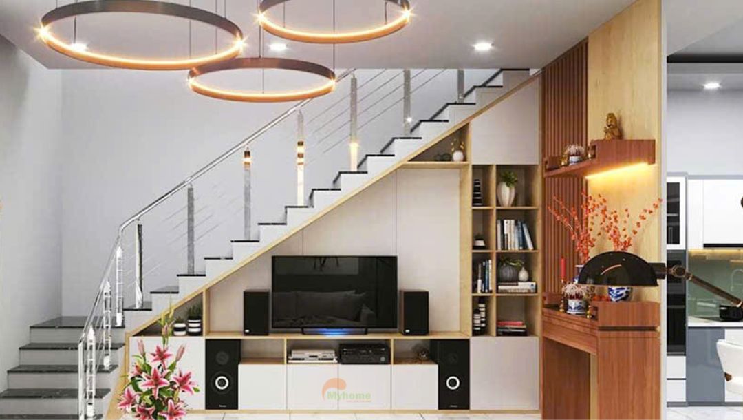 Với thiết kế nhà phố hiện đại, cầu thang thường được đặt giữa nhà. Chính vì thế vị trí gầm cầu thang thường được tận dụng thiết kế vách tivi phòng khách.